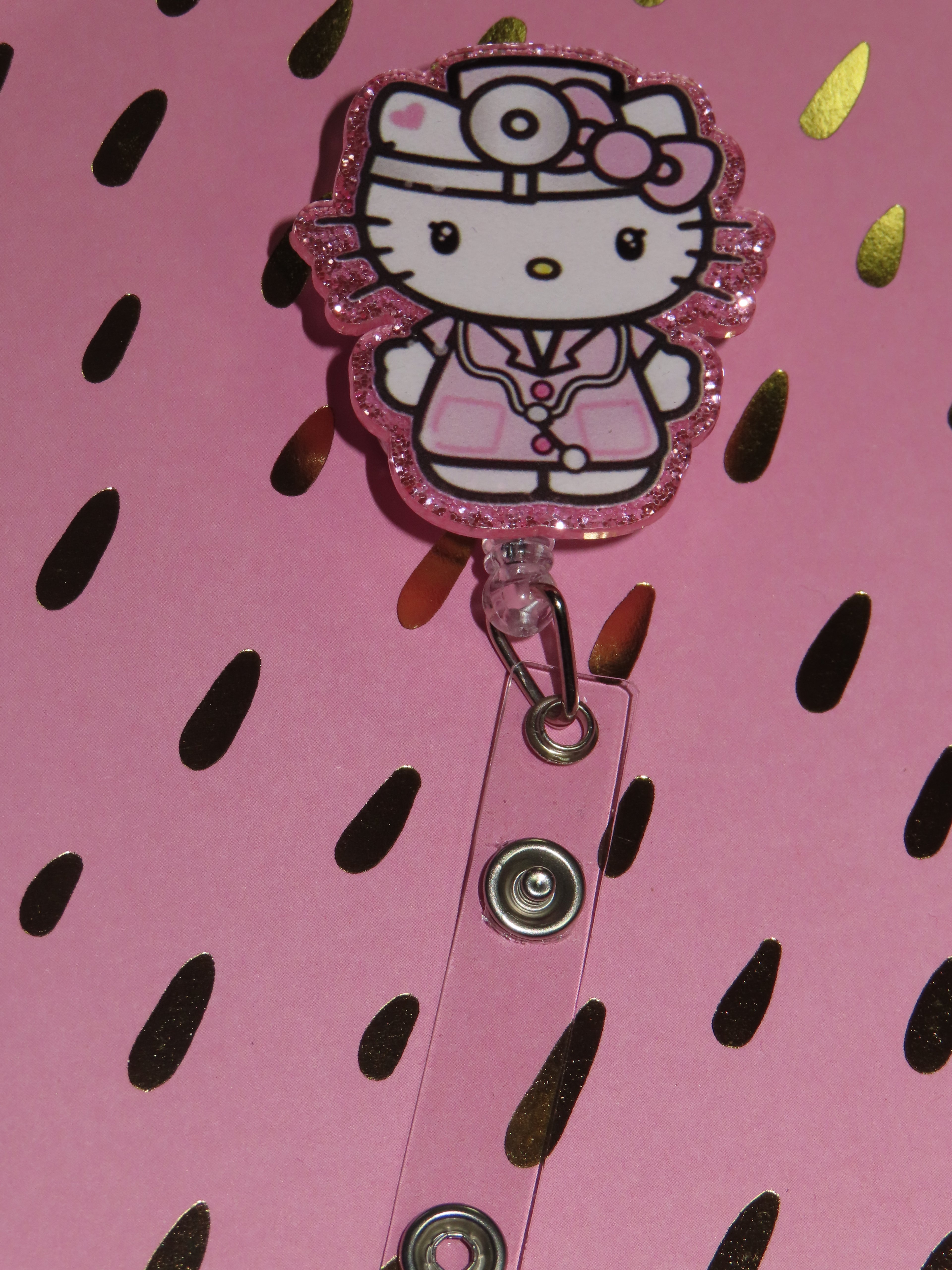 Hello Kitty character in a doctor's outfit on a pink background with black shapes